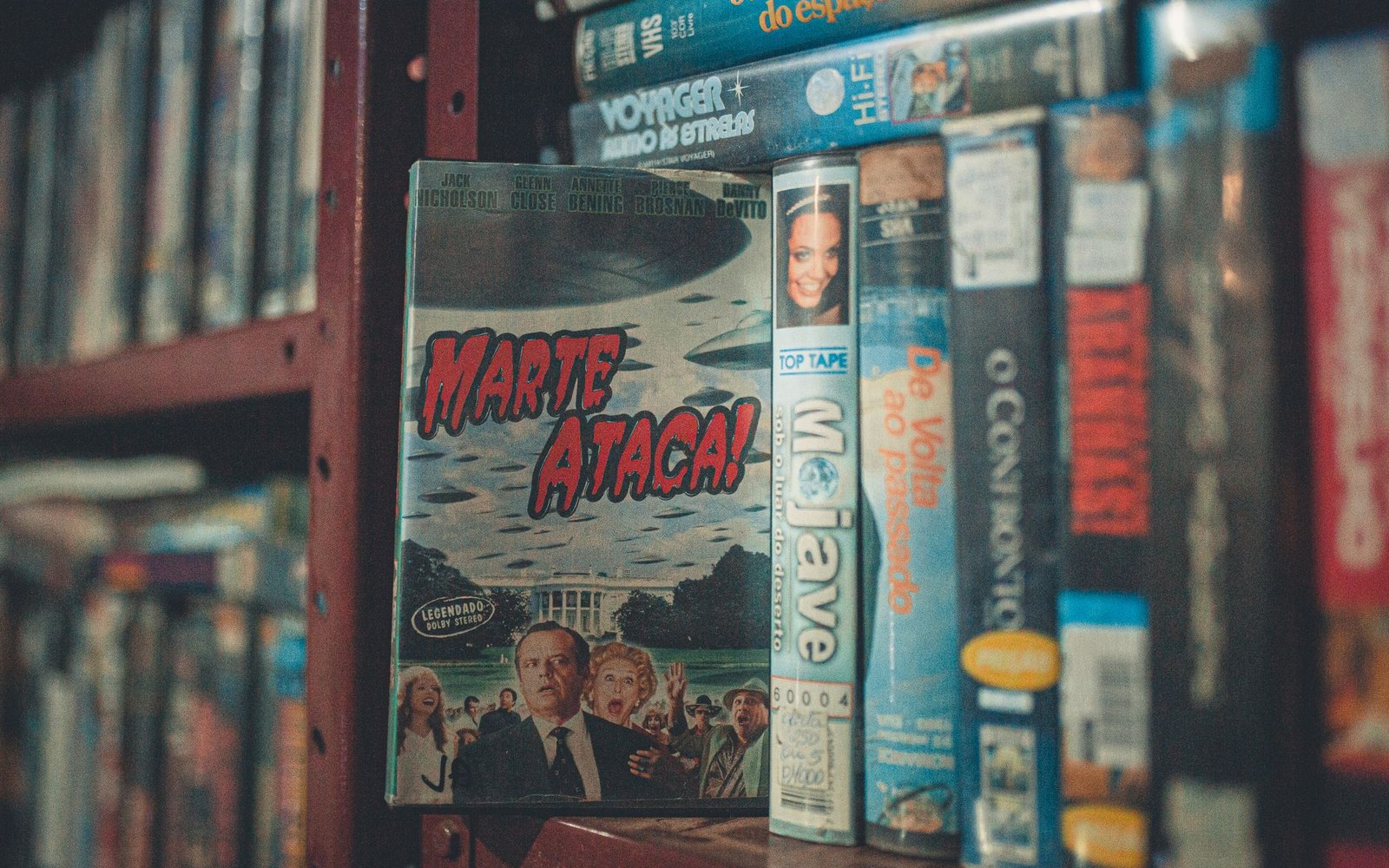 A "Marte Ataca!" DVD case stands upright among VHS tapes on a shelf