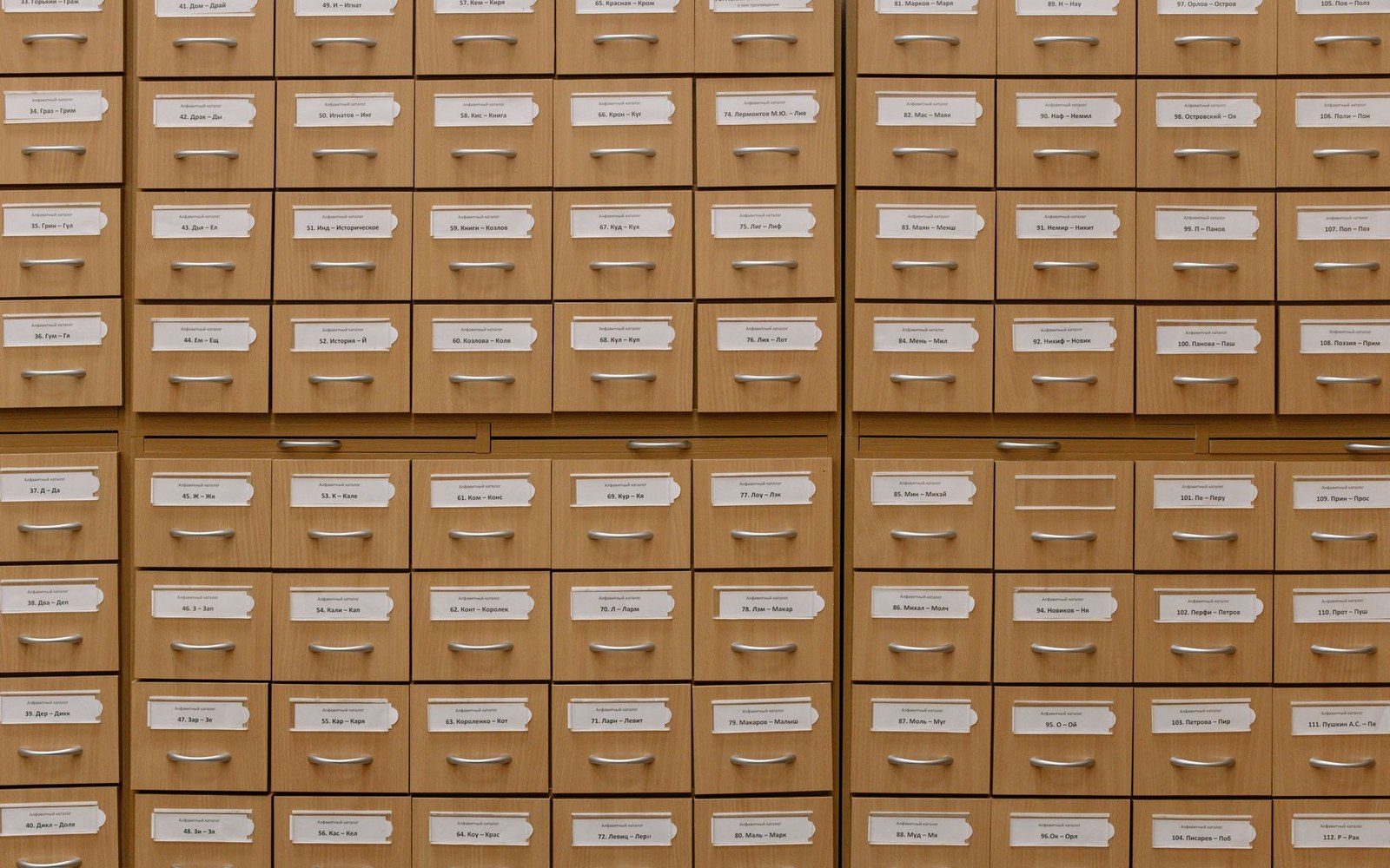 Rows of wooden library card catalogue drawers with labeled paper index tags