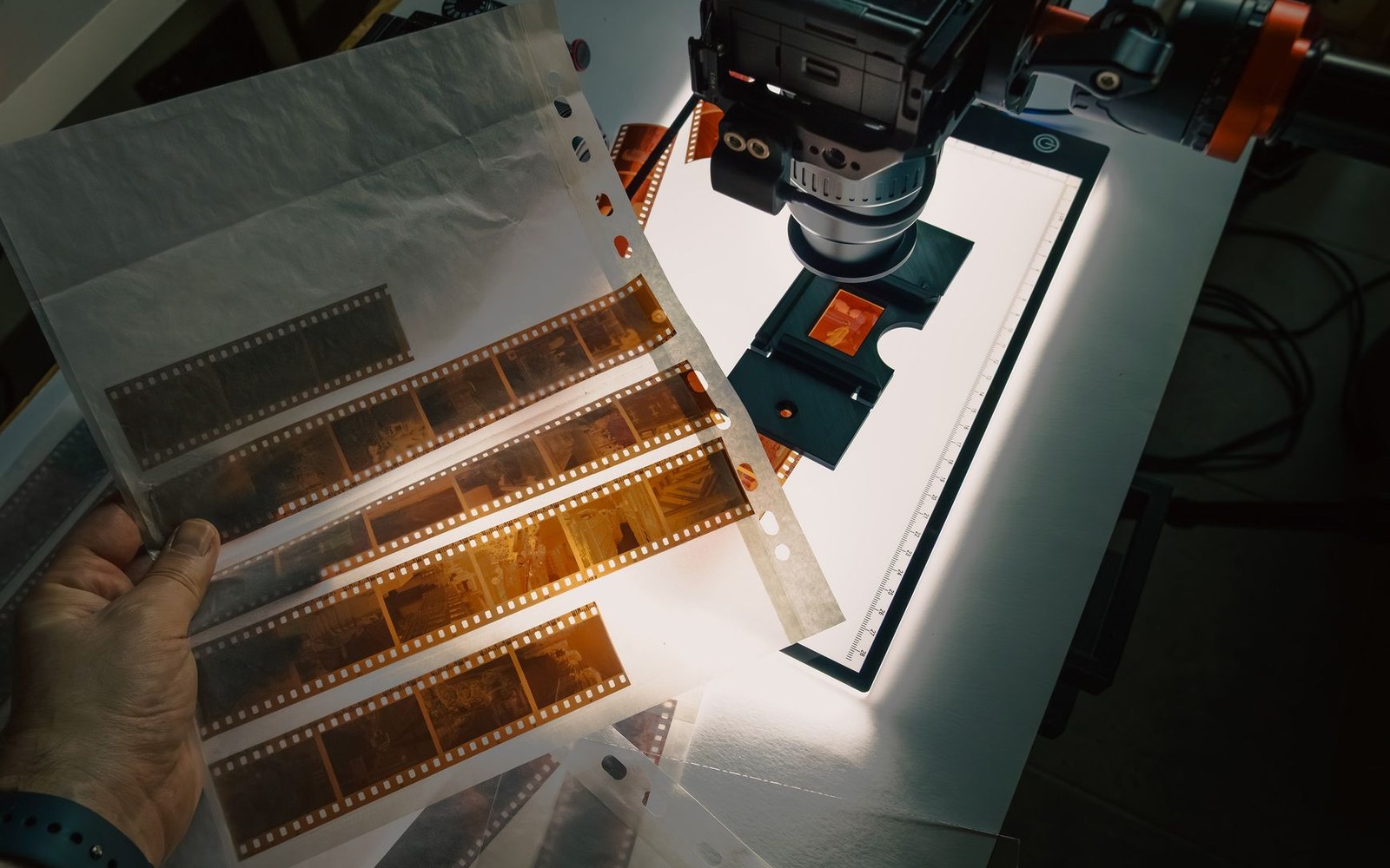 Holding negative film strips over a lightbox with a camera mounted for digitizing
