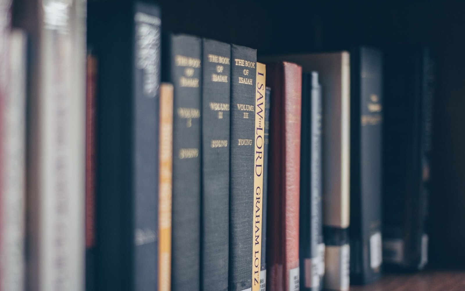 Rows of hardcover book spines on a shelf, including volumes of The Book of Isaiah