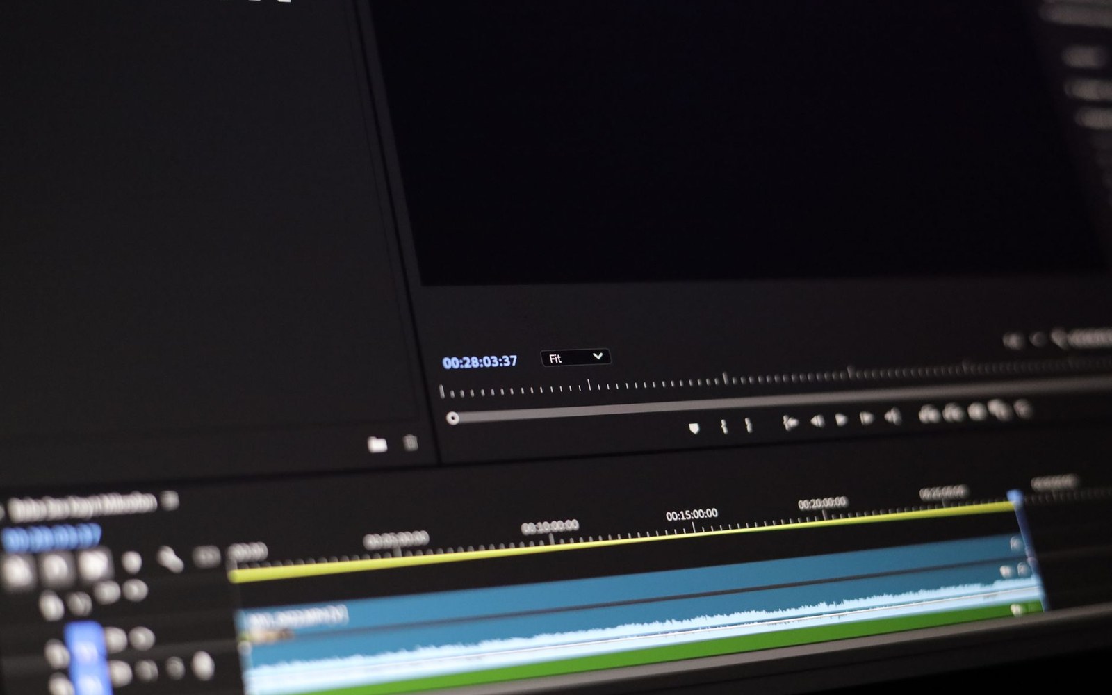 A Steenbeck flatbed editing table with a frame frozen on its small screen, an editor's hands on the controls, the editing room visible in the background
